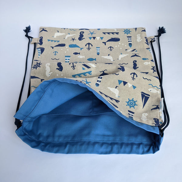 Open Nautical drawstring backpack with medium blue lining and navy drawcords. two internal pockets