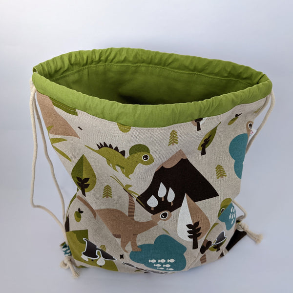 Open baby dinosaur drawstring bag showing green lining