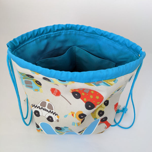 Inside view of Toy vehicles drawstring bag with turquoise lining and drawcords. Two internal pockets.